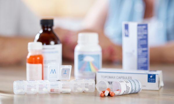 Cropped shot of medication on a kitchen table with an unrecognizable couple in the background.