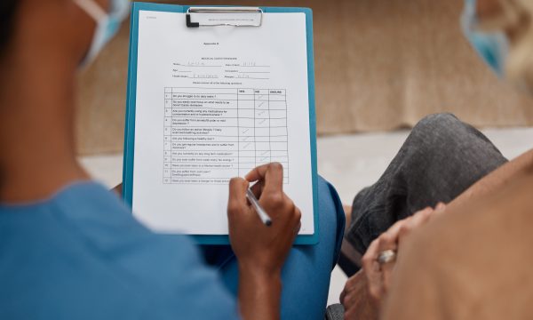 Shot of a doctor filling out a questionnaire during a consultation with a senior woman at home.